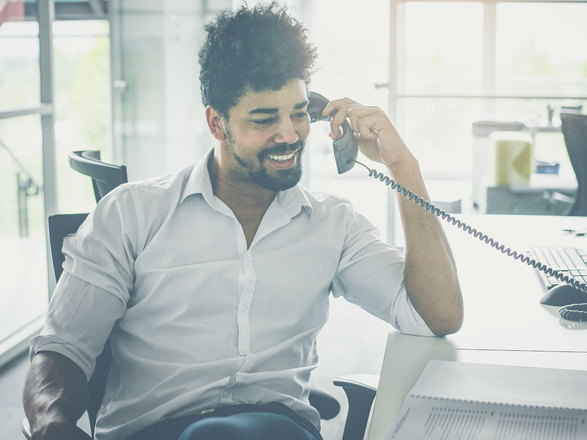 A businessman talking on a phone at his desk.