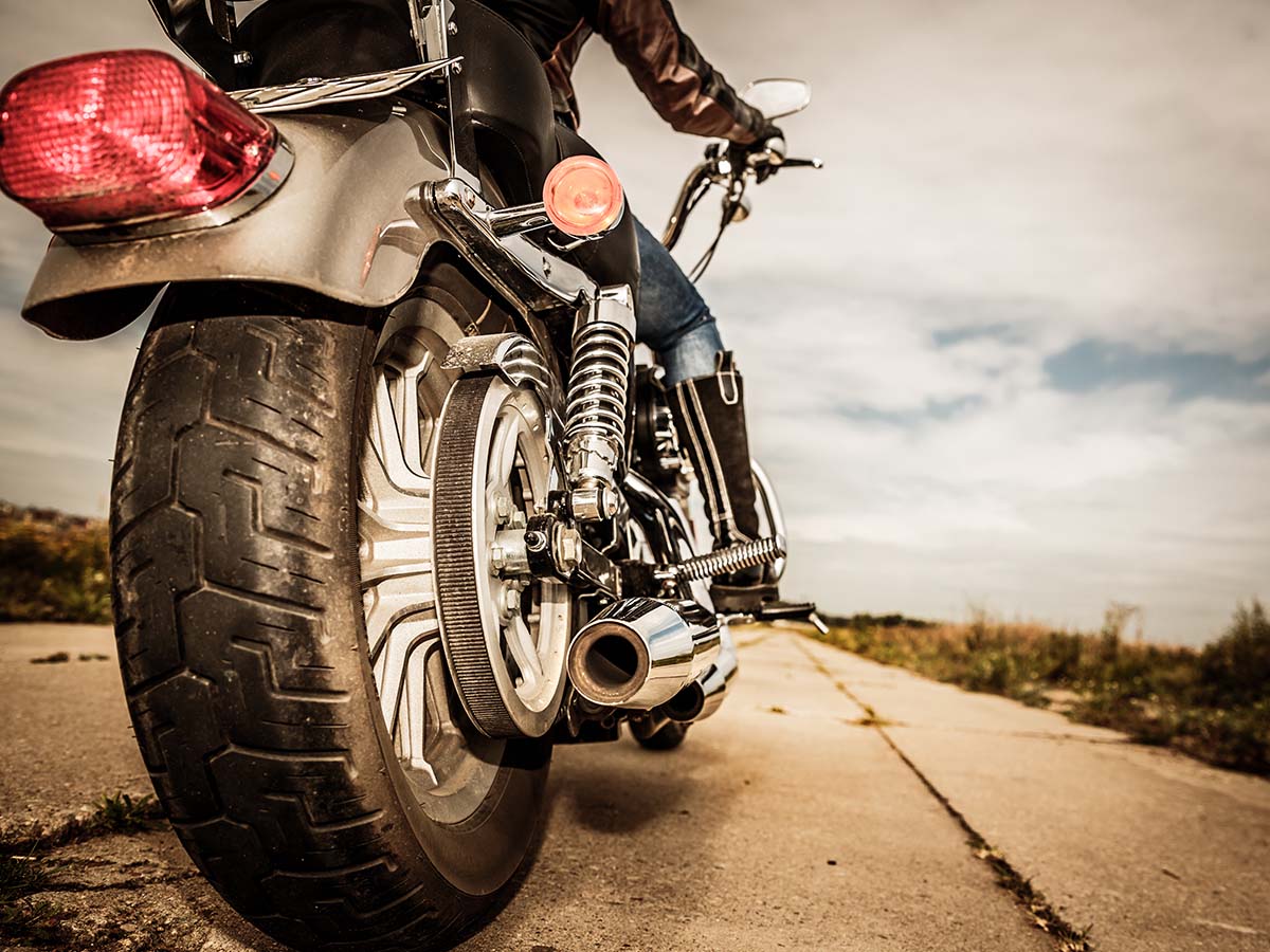 The view of a back tire of a stopped motorcycle. 