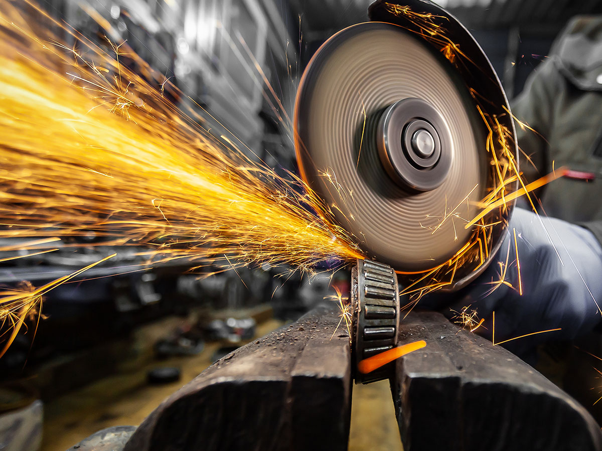A car mechanic using a metal grinder in an auto repair shop.